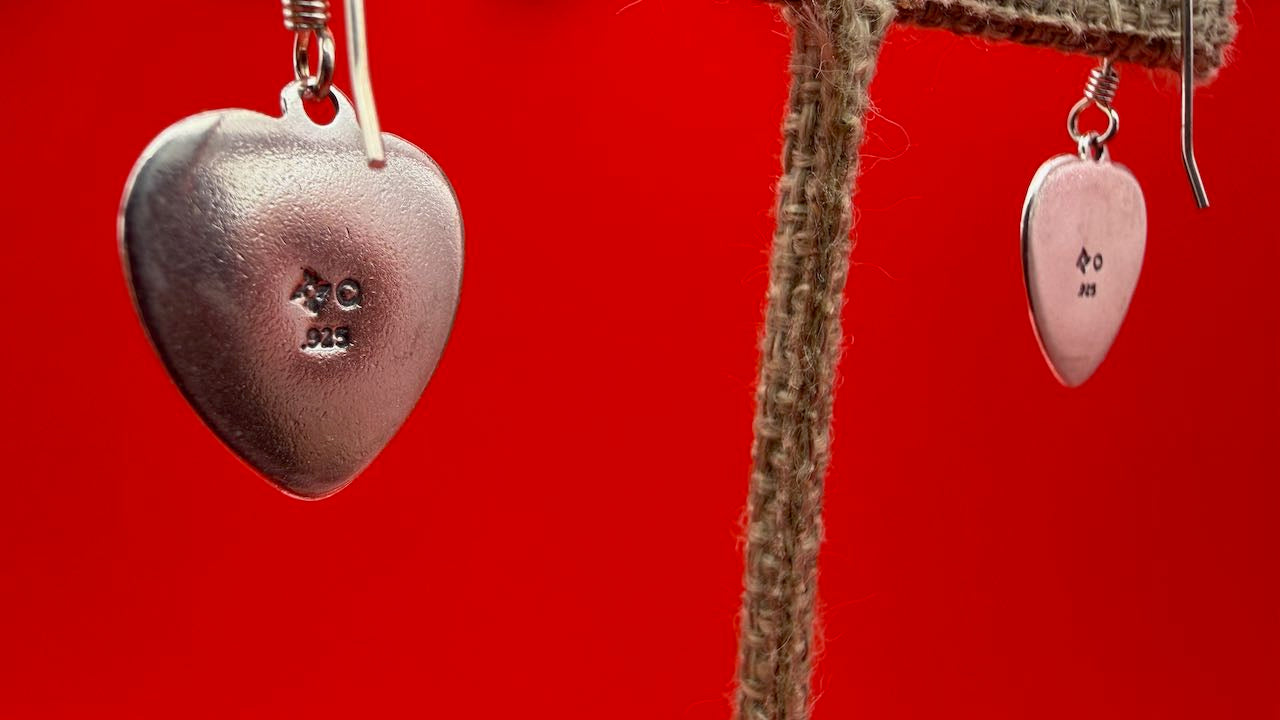 Heart-shaped silver earrings on a red background